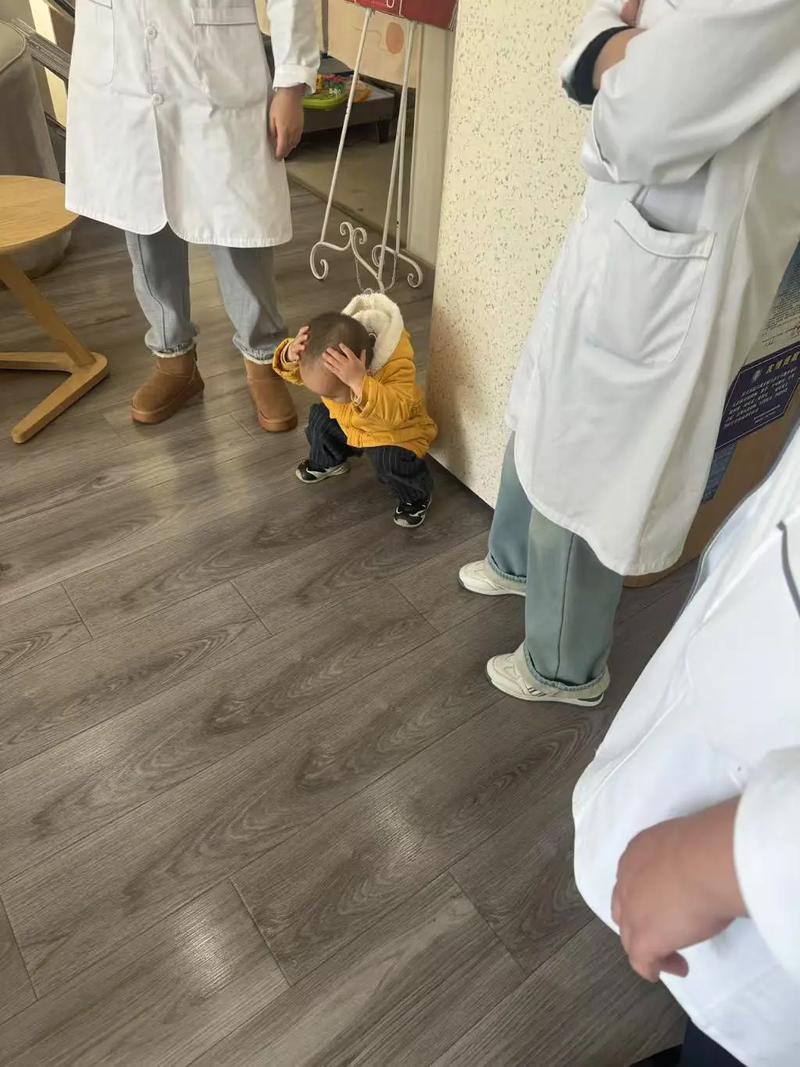 幼儿轻轻拍着蹲下的妈妈的头安慰