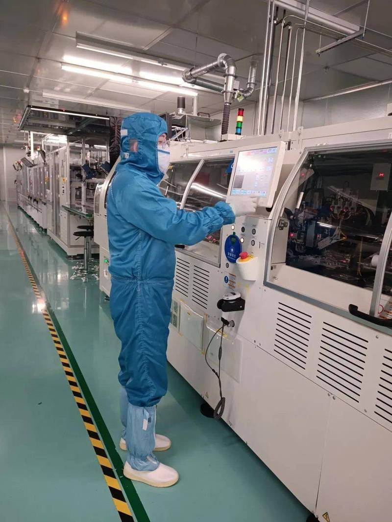 无尘车间内工程师穿全套无尘服操作晶圆传送设备