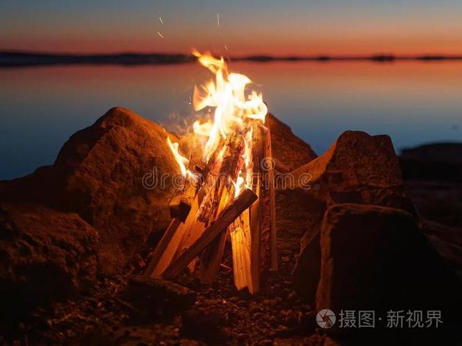 夜晚沙滩上篝火燃烧特写，火星飞舞