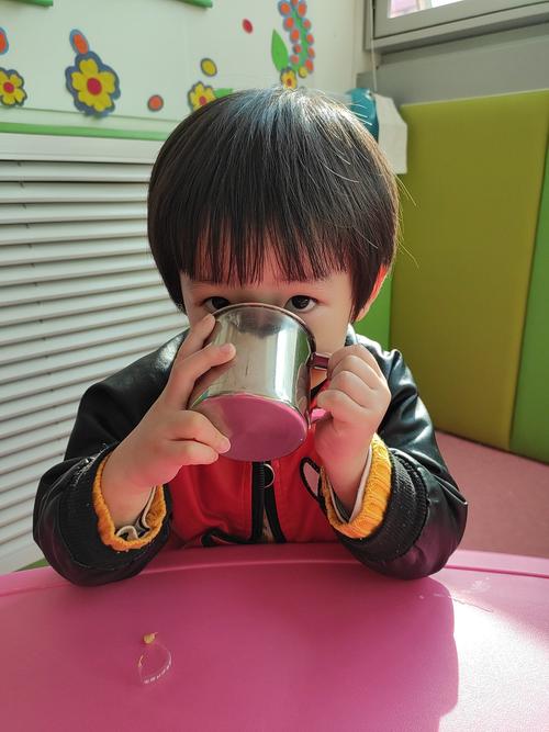 孩子蹲在厨房操作台边盯着玻璃杯里的糖水看