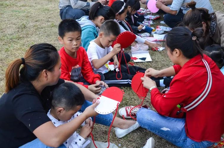 父母和幼儿一起在草坪做手工玩耍图