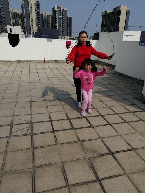 傍晚小区楼下陪孩子跳绳的年轻母亲