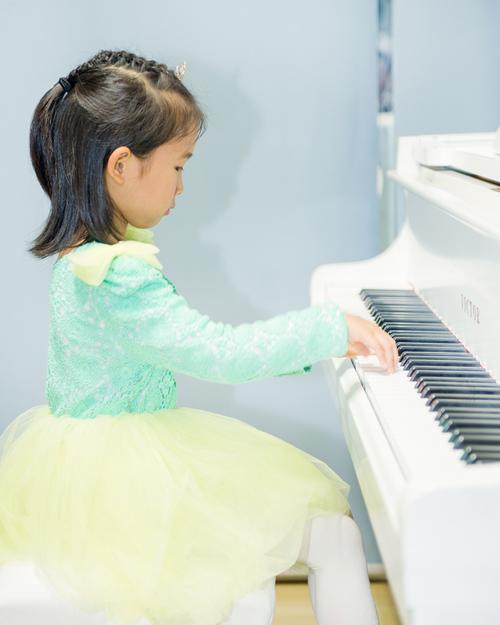 小学一年级孩子坐在钢琴前皱着眉摸琴键