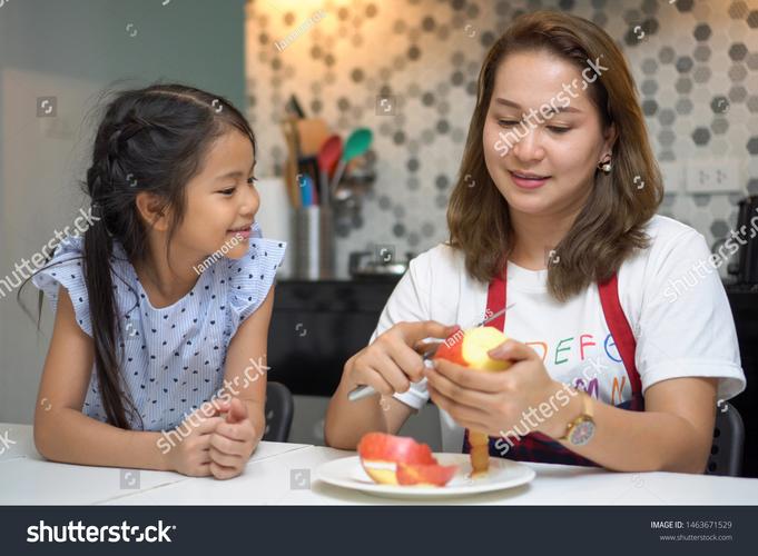 妈妈和女儿在超市水果区触摸奇异果