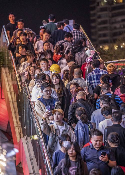 摄影师用长焦镜头在拥挤景区拍摄孤立主体
