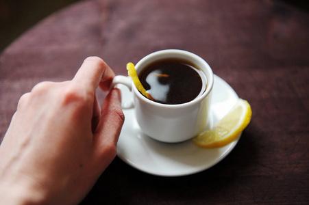 浅烘焙咖啡豆在白色杯子里 旁边放着柠檬和橙皮 阳光照在杯沿