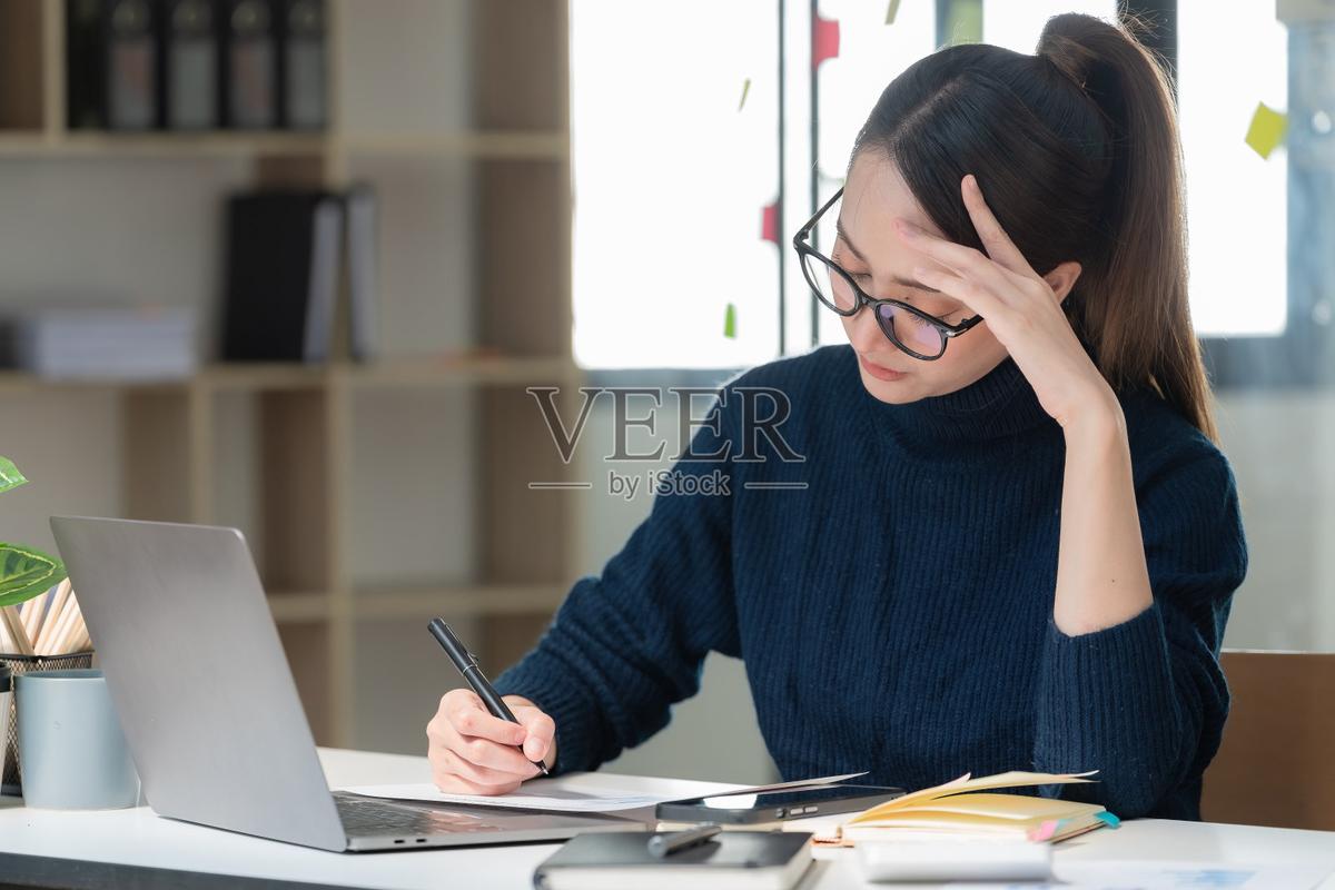 坐在书桌前摸着后颈皱眉的上班族