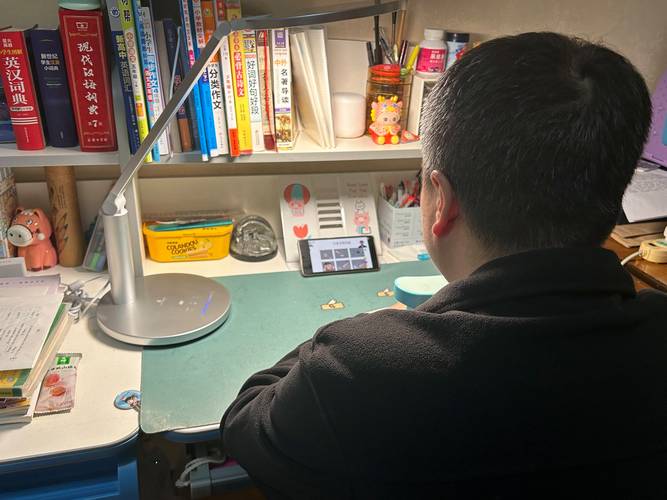 家长蹲在中学生书桌旁看电脑屏幕
