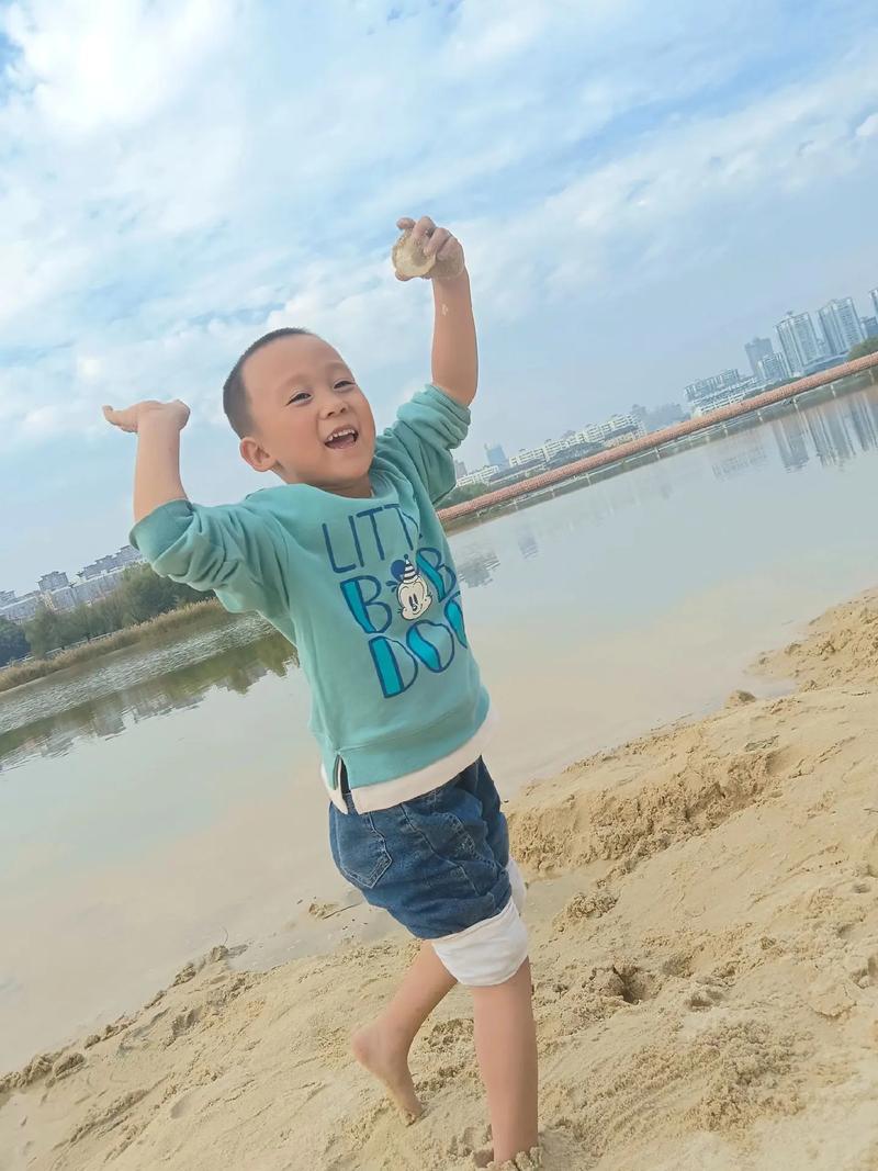 5岁小男孩在沙坑里尽情玩耍，满脸笑容