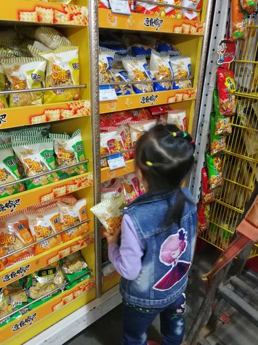 超市货架前家长蹲地上核对宝宝零食配料表实拍图