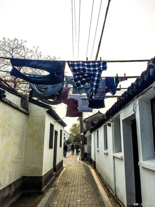 江南苏州老宅巷口晒旧被褥场景