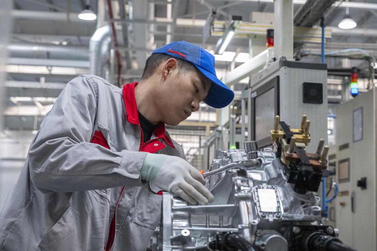 装配线工人专注检查汽车发动机零部件