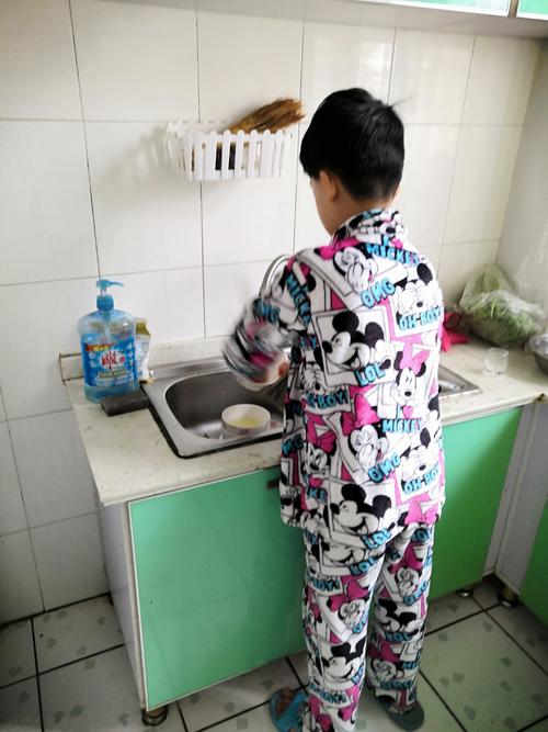 小男孩低着头站在厨房门口攥着衣角听妈妈说话的日常场景