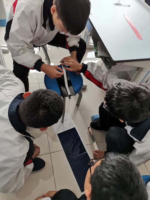 初中生蹲在走廊地面上修改实验设计方案的特写