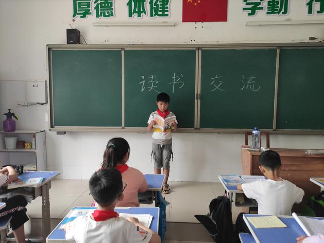小学教室窗边孩子举着手分享读书感受