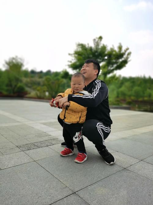穿工装的父亲蹲下来抱幼儿园孩子