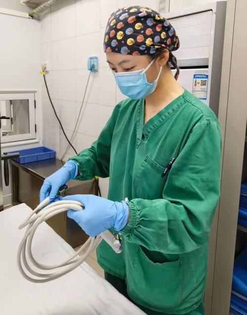 护士在母乳库操作巴氏消毒设备，穿着隔离服