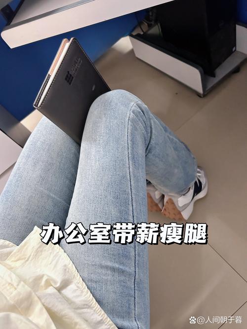 办公室工位上坐姿抬腿练大腿肌肉的上班族