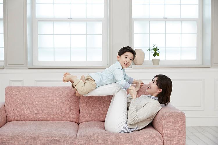 年轻妈妈在沙发轻松陪孩子玩耍