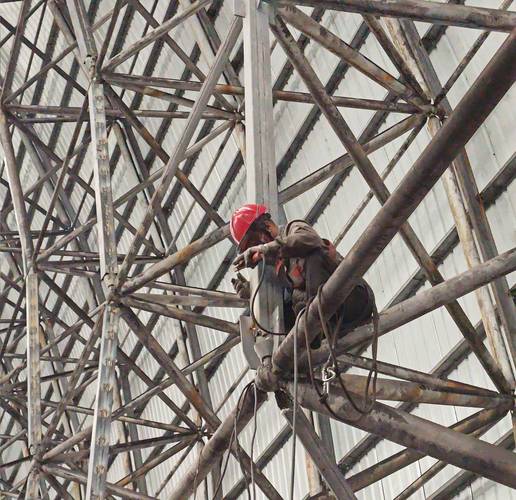 工人正在高层建筑外架张挂安全网,示范系结点正确绑扎方法