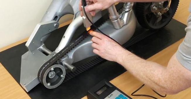 运维师傅用手指按压检测工业皮带张紧度的现场图