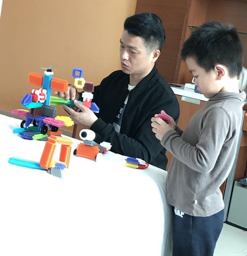 制造业父亲拿着孩子手工拼的机械模型对视笑的场景