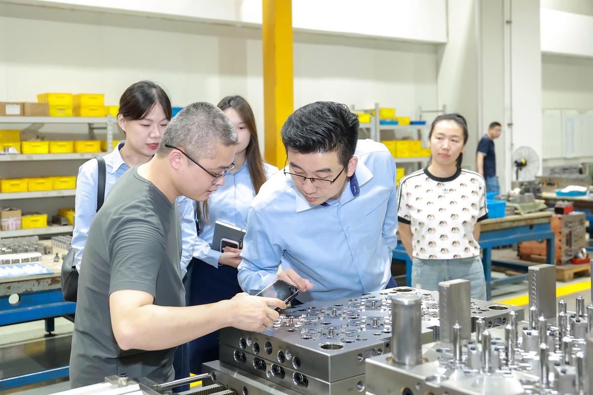 高校导师与企业工程师在注塑产线现场讨论工艺参数