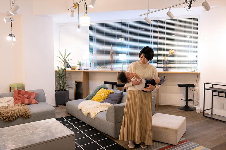 大宝躲在墙角看妈妈抱二宝的居家客厅场景