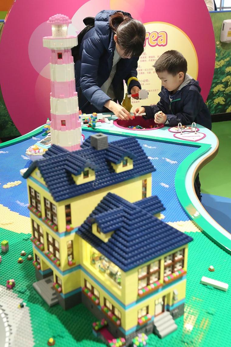 父母和两个孩子趴在地板上拼乐高城堡的温馨画面