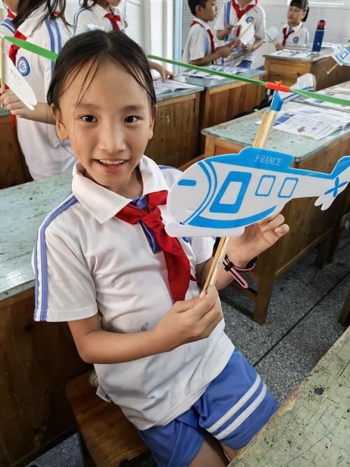 小学航模社团学生课后在走廊调试自制橡皮筋动力飞机