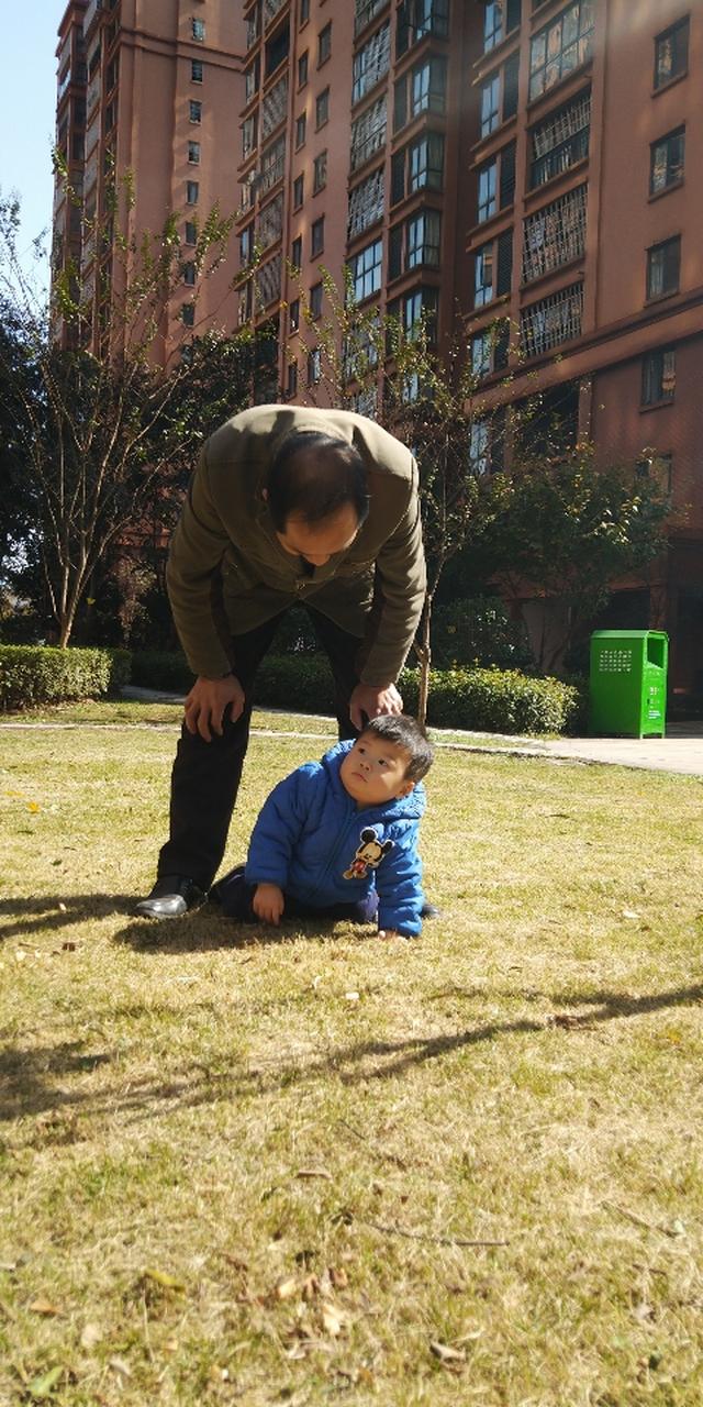 城市亲子公园沙坑边低头玩手机的父亲