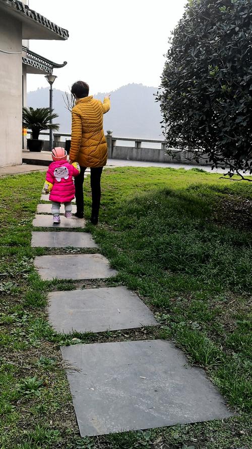 校门口花坛边母子踩地砖缝隙的背影