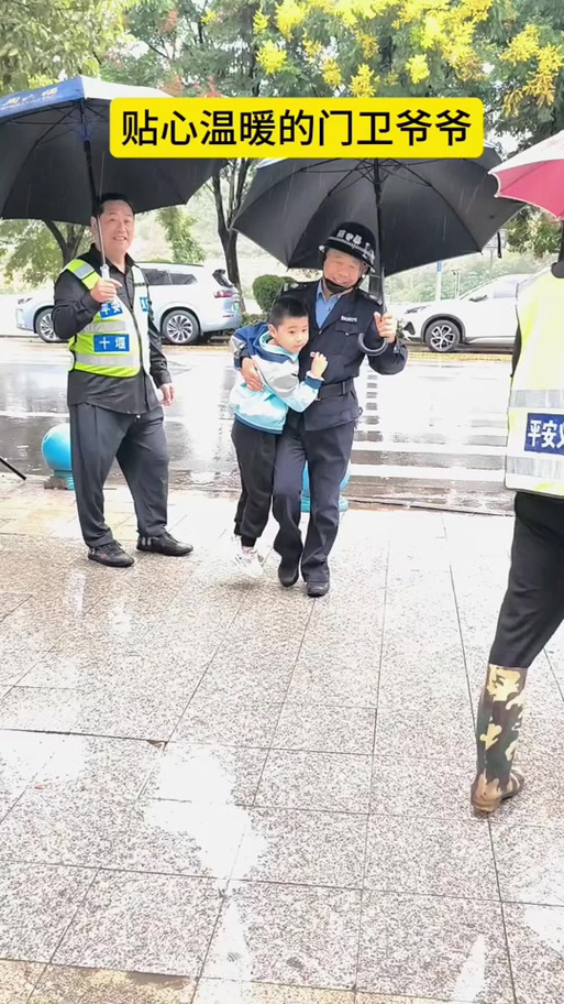 中学保安雨天撑伞送低年级学生进校 半边肩膀被淋湿