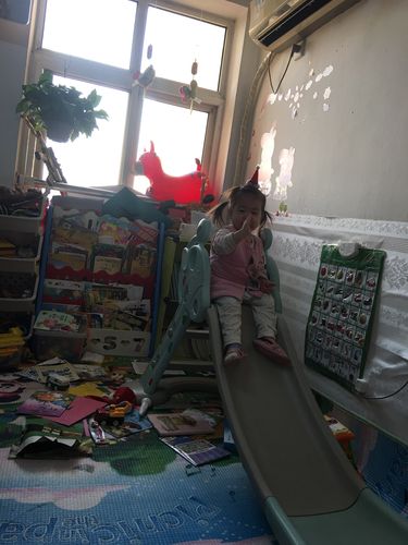 企业员工宿舍滑滑梯旁幼儿攥着零食不肯松手的实拍场景