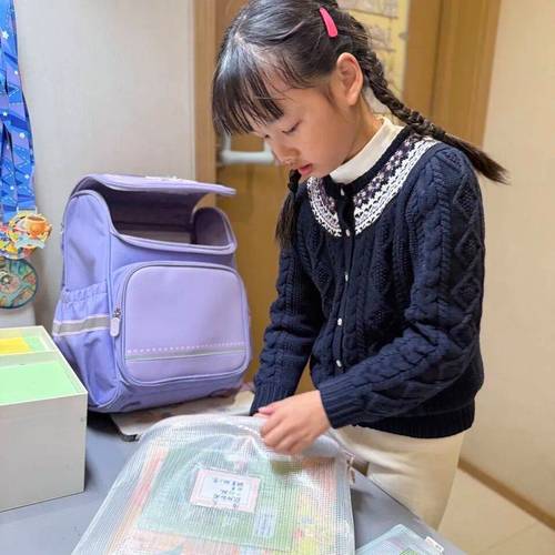 小学孩子写完作业把课本整理进书包的实拍场景