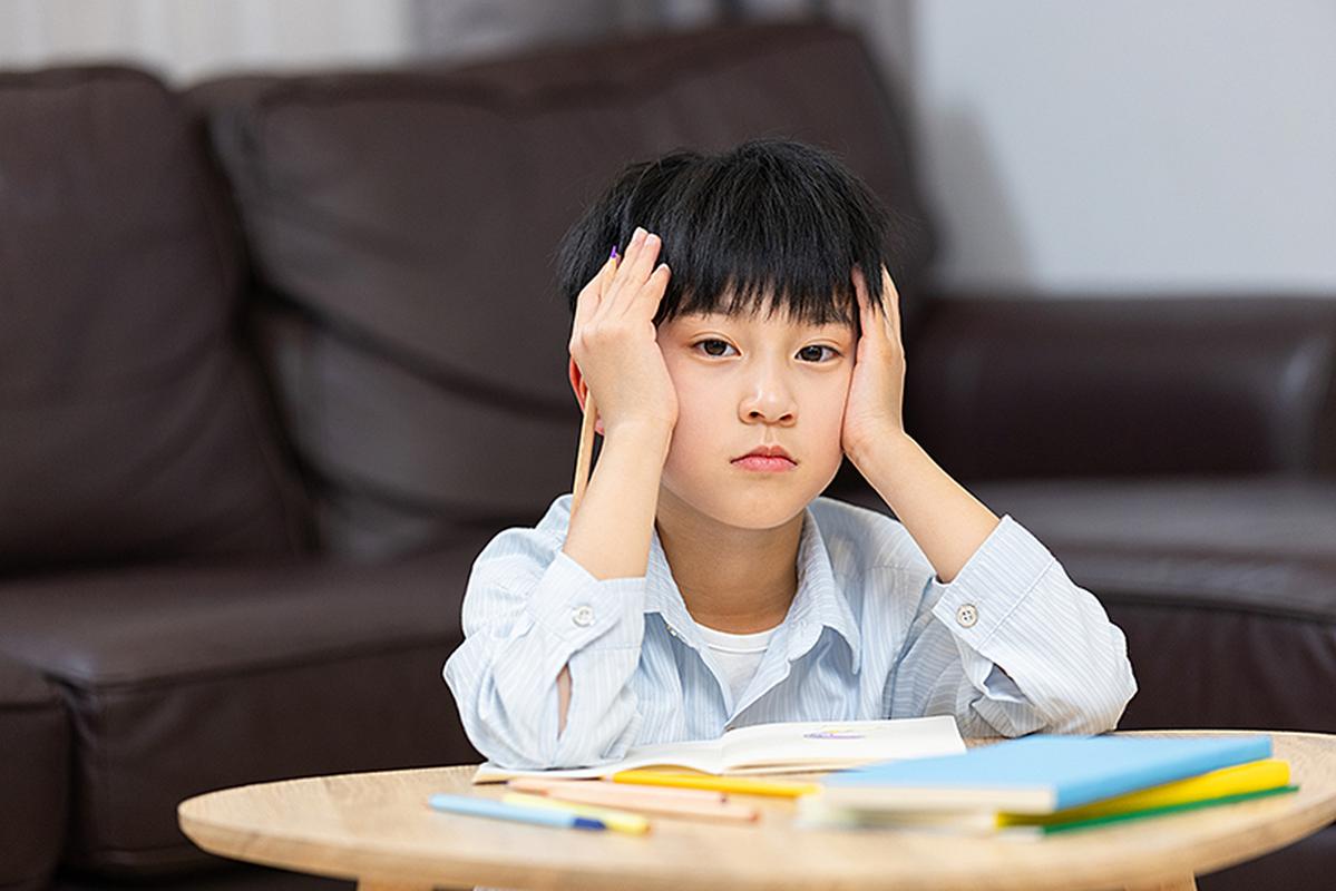 小学低年级孩子书桌前分心盯着窗台西瓜虫的真实生活照