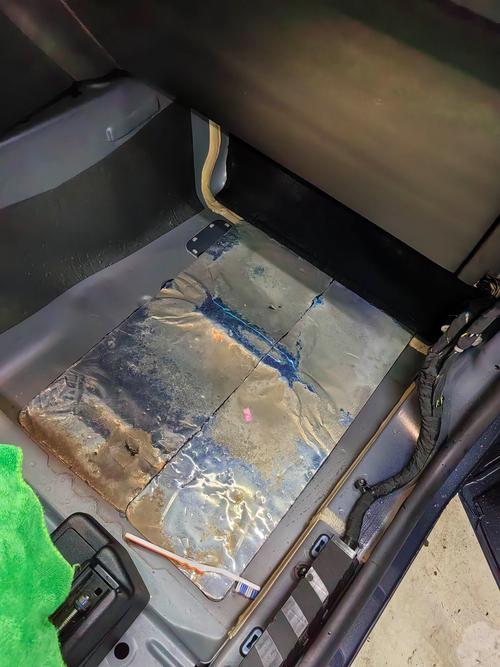 汽修车间内技师拉开车主副驾脚垫找漏电点场景