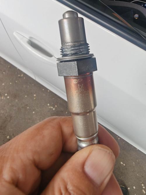 汽修店举升机上拆下来的旧汽车前氧传感器特写