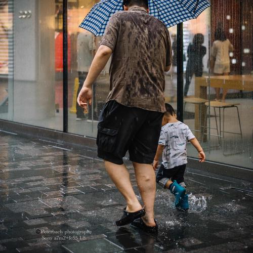 雨天公园父子踩水坑背影照片