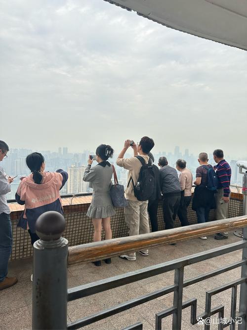 游客在景区地标前举起手机拍照的俯拍画面
