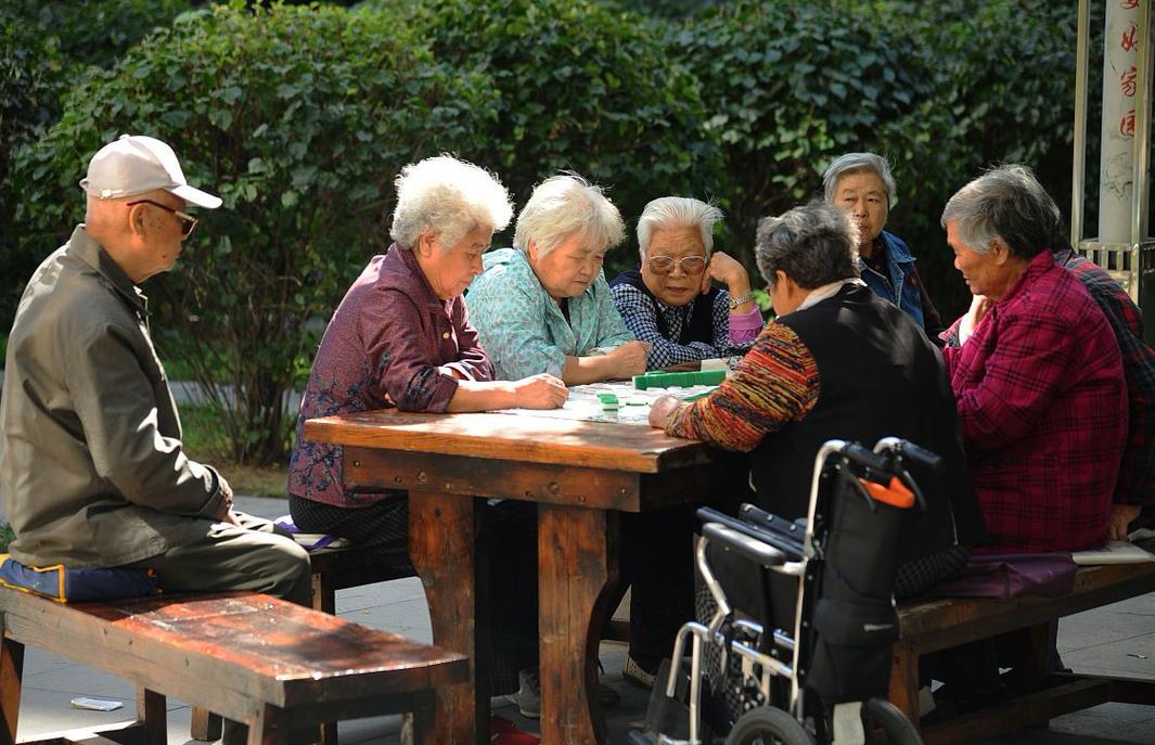 老小区花园里几个老年街坊围坐在一起择菜聊天的场景