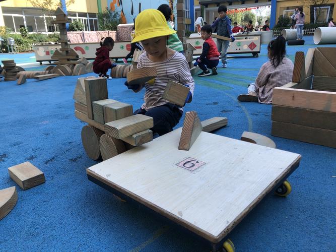 幼儿园小朋友户外搭斜坡积木滑小车场景