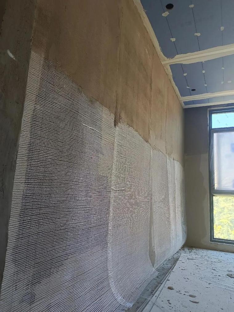 墙面铺设玻纤网压入腻子层施工场景