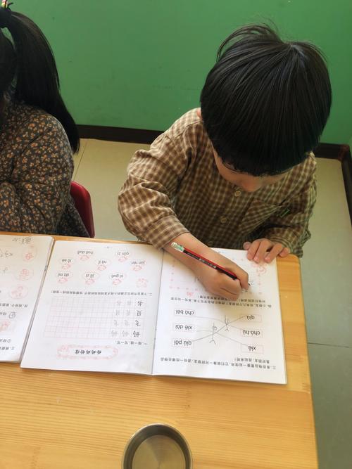 母子俩趴在书桌前一起用红笔圈数学题单位的场景