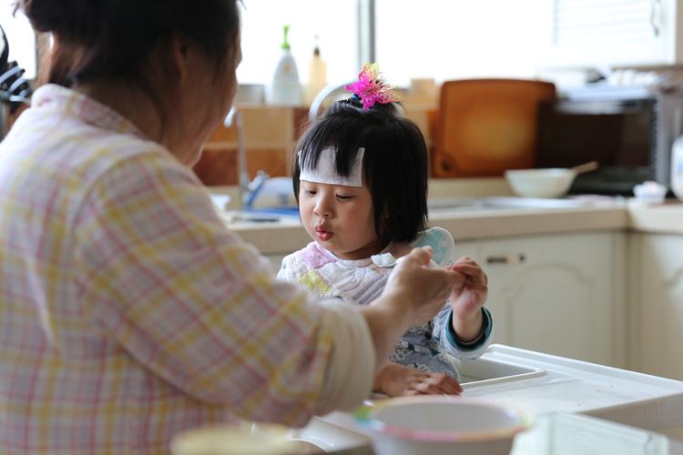 妈妈靠在床头和生病的小孩分吃橘子糖的居家场景