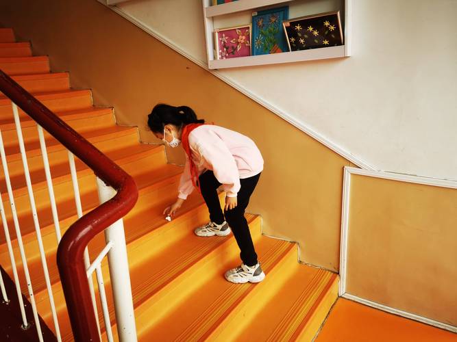 小学教学楼走廊转角 穿校服的学生蹲在垃圾桶旁
