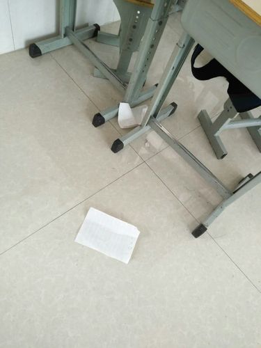 高中走廊瓷砖地上散落的学生作业本与红笔