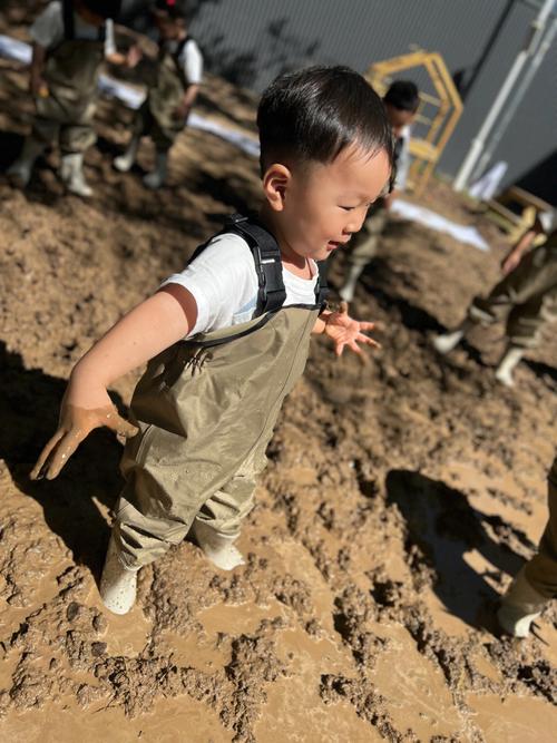 4岁幼儿蹲在小区花坛边玩湿泥巴的实拍