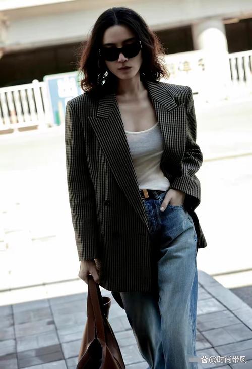 一位年轻女性穿着80年代复古西装外套搭配现代牛仔裤，站在街头