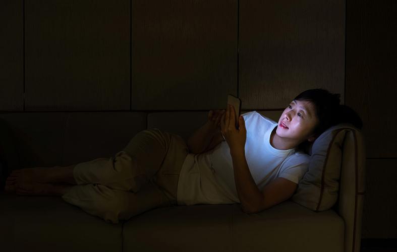 夜晚客厅沙发刷手机犯困的年轻人